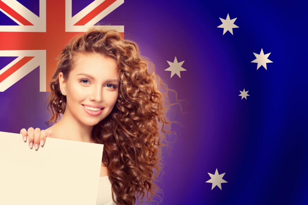 Smiling student holding a sign in front of the Australian flag, representing affordable study abroad programs in Australia for international students